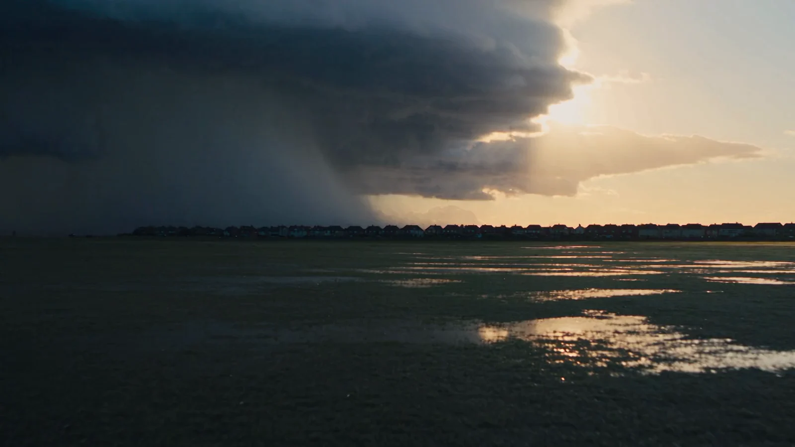 Open land under a storm on the left, the light breaking through on the right